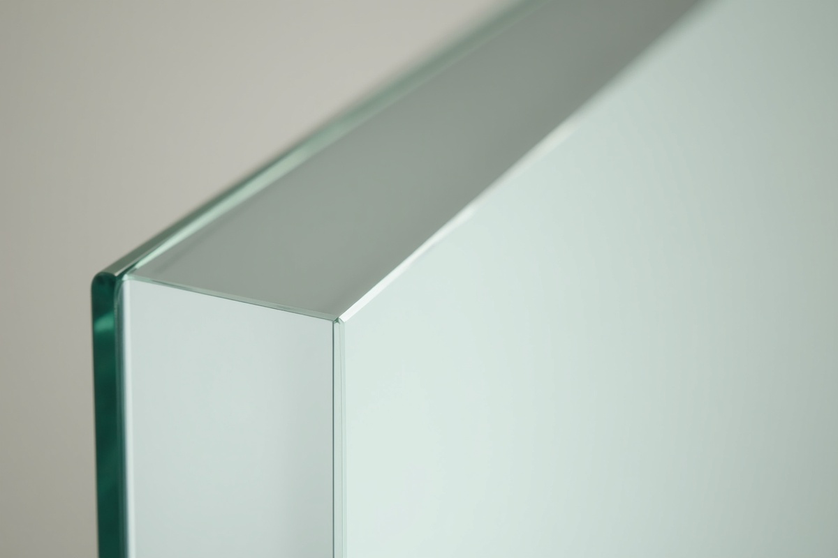 Close-up of beveled edge on custom bathroom mirror showing the light-catching angled perimeter on a clear mirror panel