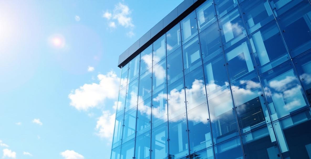 Commercial high-rise building with a full-height glass curtain wall facade reflecting the Texas sky across Dallas