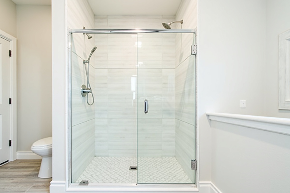 Frameless pivot shower door installed in a Coppell TX alcove shower with subway tile and chrome hardware finish